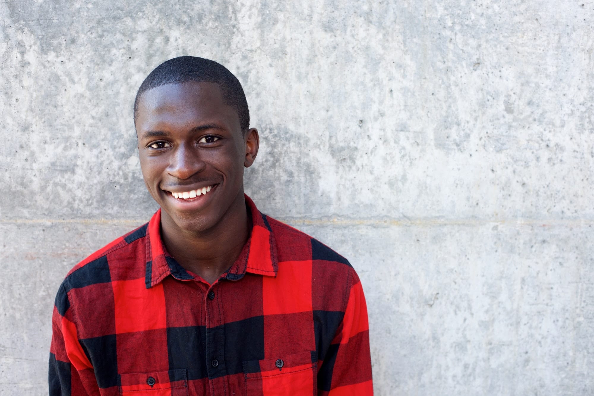 Smiling young african male model standing against wall